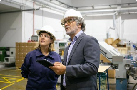 Dos profesionales con casco recorriendo una planta industrial